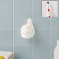 White hand-shaped wall clip holding keys and cables with thumb grip