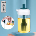 Glass oil dispenser with brush in use, applying oil to food on a cooking pan.