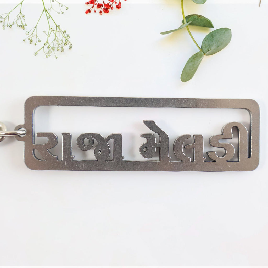 Gujarati text metal keychain featuring devotional design