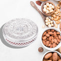 Elegant round dry fruit box with three compartments on a table.