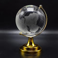 Crystal World Globe (50mm) with golden stand on a wooden surface.