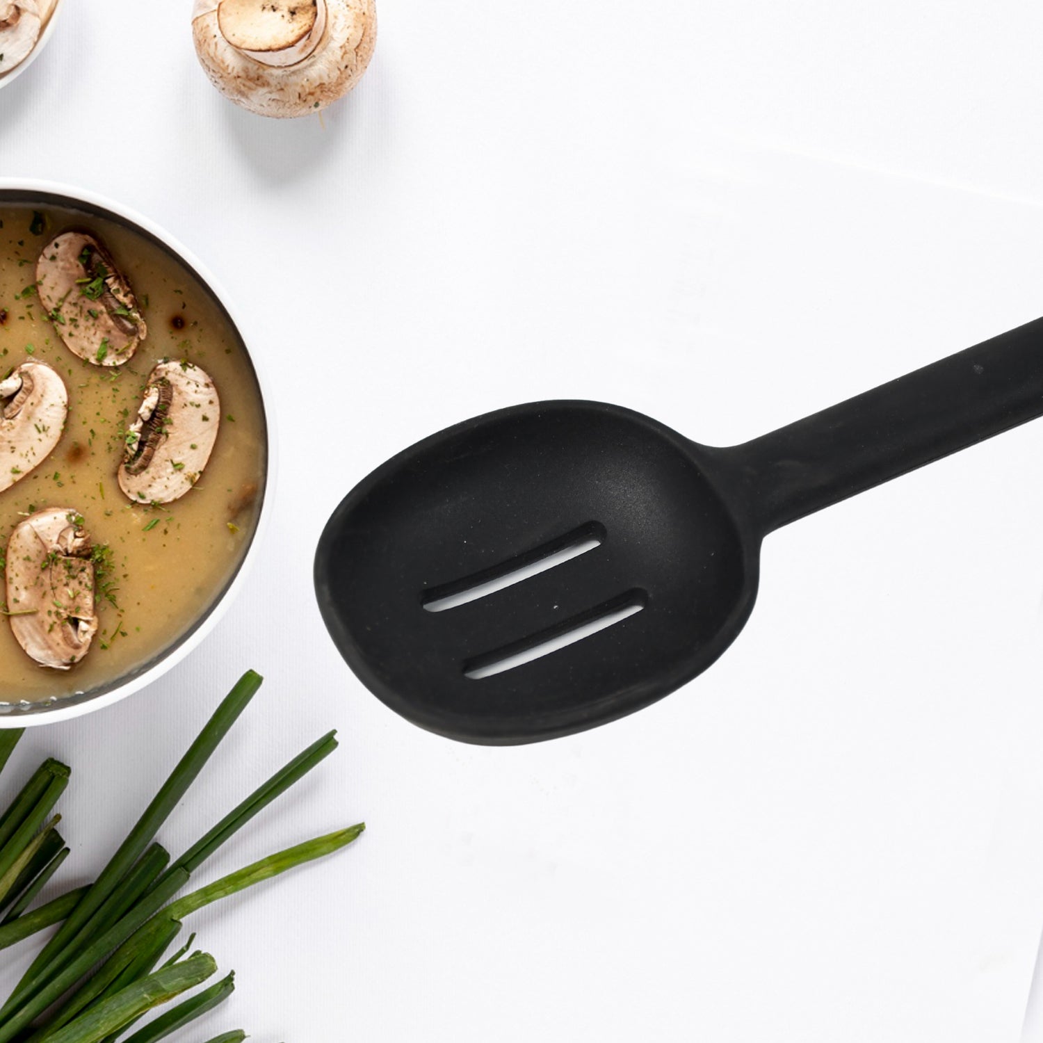 Heat-resistant silicone spoon stirring food in a non-stick pan.