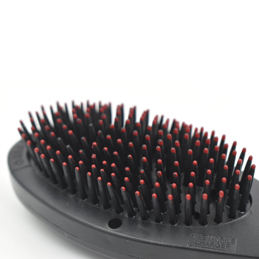 Close-up of the electric hair massager comb's bristles and power button.