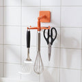 Orange rotating kitchen utensils hook stand mounted on kitchen wall