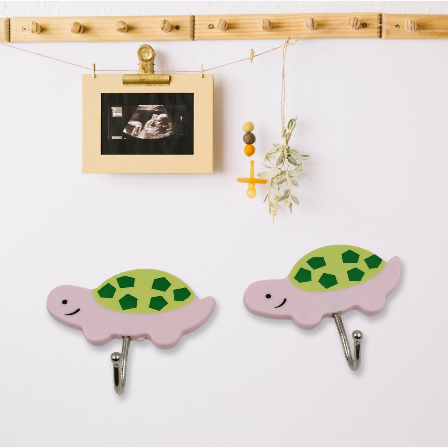 A cartoon-shaped self-adhesive wall hook securely holding a small towel on a tiled bathroom wall.