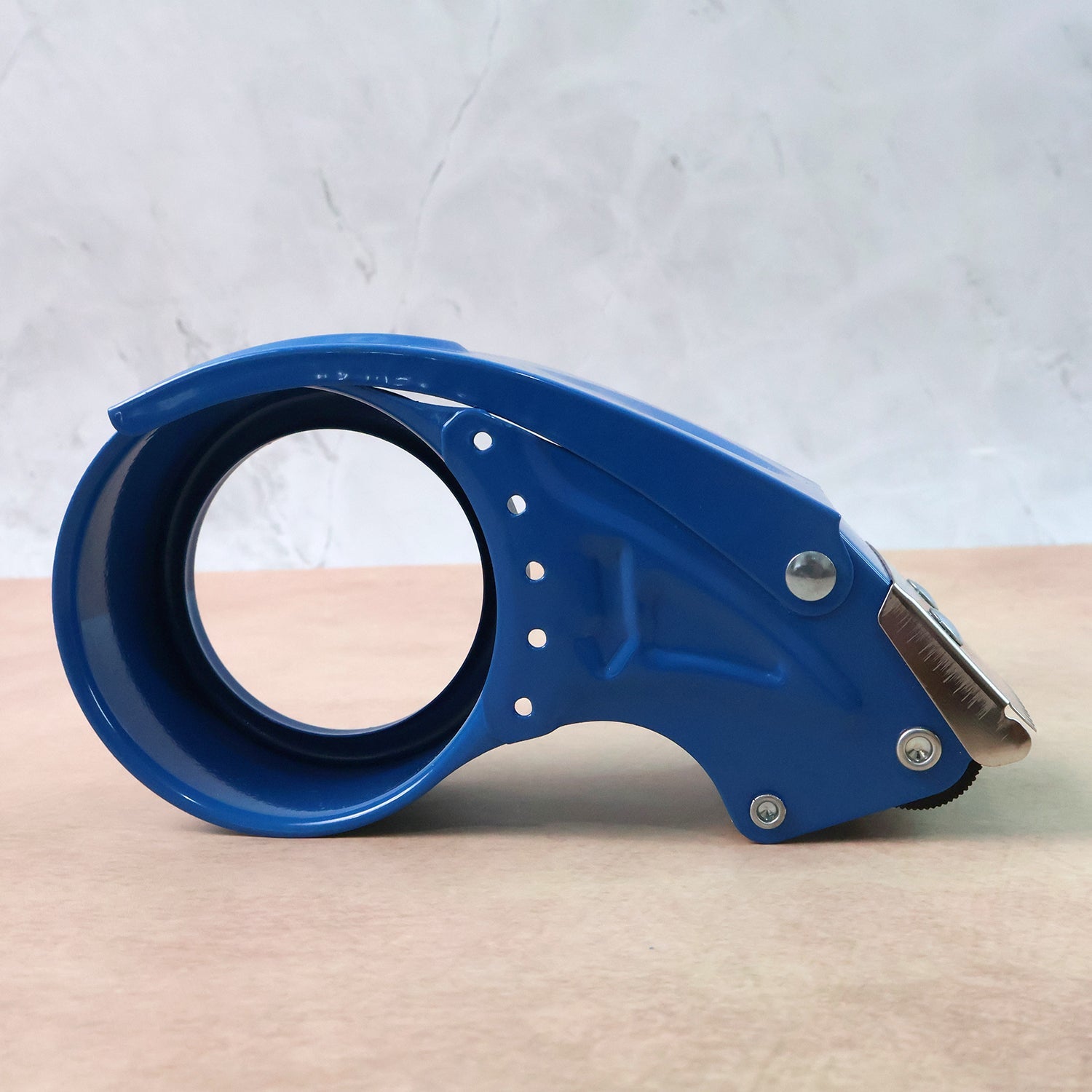 Smooth tape dispensing from heavy-duty packing tape gun with serrated blade