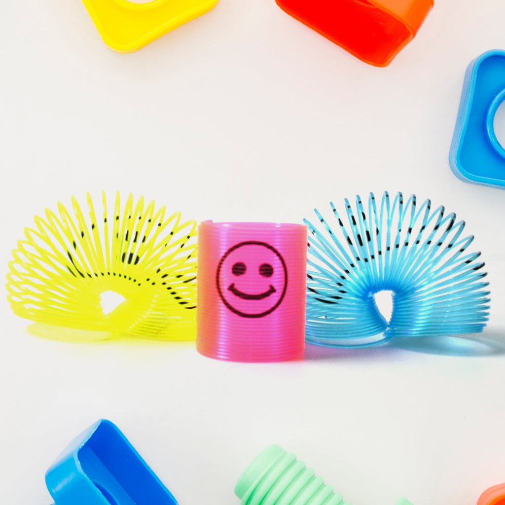 Multiple vibrant slinky spring toys neatly stacked together.