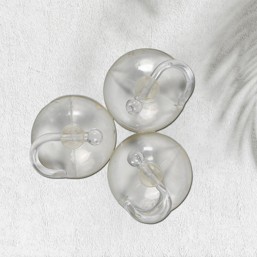 Two transparent suction hooks with strong hold on a bathroom tile wall.