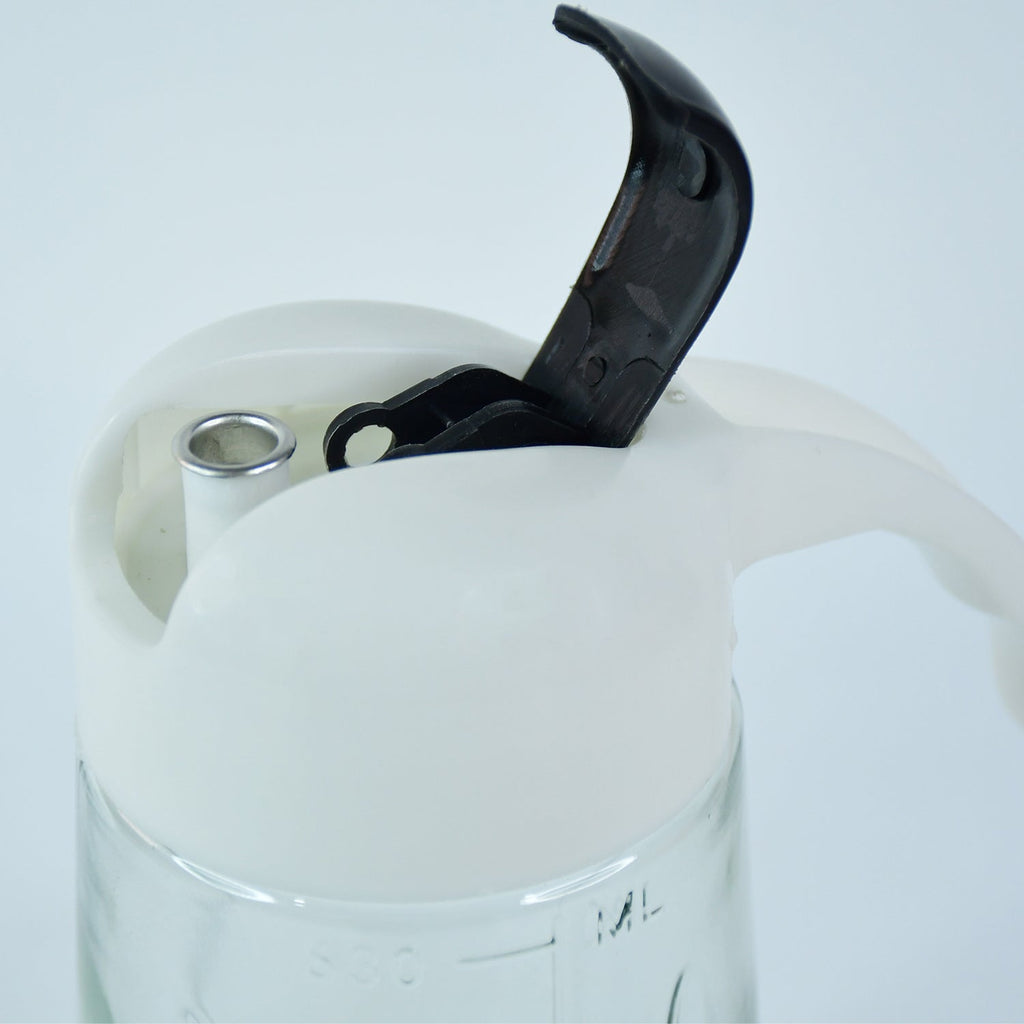 Pouring olive oil using glass oil bottle dispenser in kitchen setting