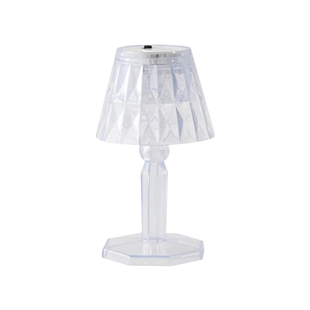 A compact crystal table lamp reflecting light onto a wall.