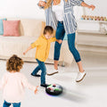 A child happily playing with the glowing Hover LED Ball indoors, showcasing its vibrant lights.