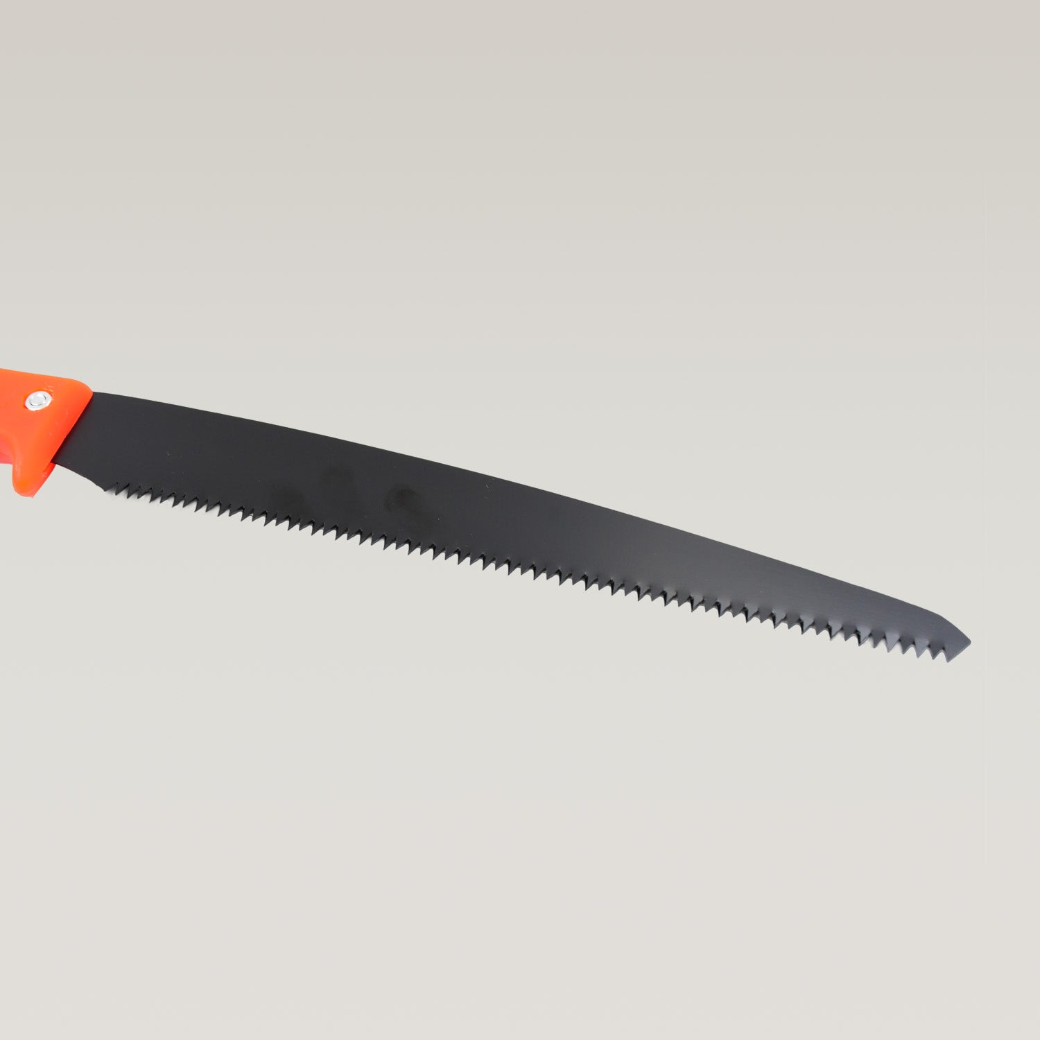 Hand pruning saw being used to cut a tree branch in a garden.
