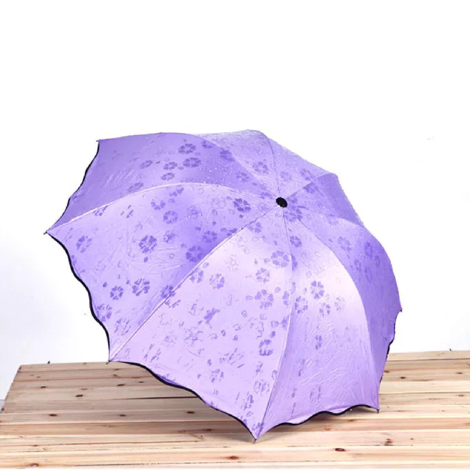 Person holding a wet Magic Umbrella with visible color-changing blossom design.