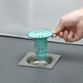 Silicone floor drain stopper preventing hair and odors in a modern bathroom.