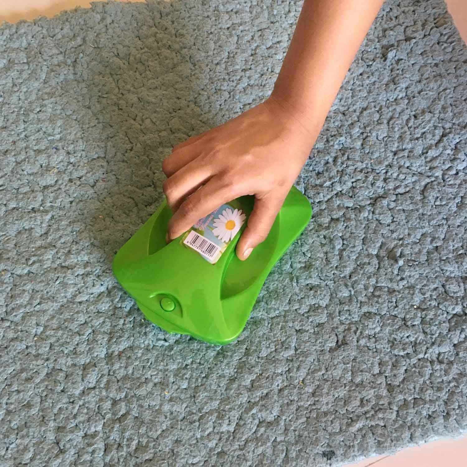 Handheld carpet roller brush efficiently cleaning dust and crumbs from a patterned rug.