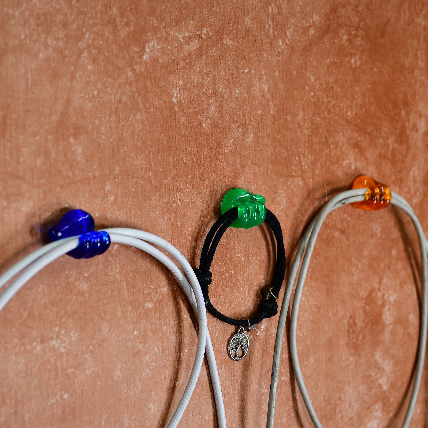 A single hand shape wall clip securing a charging cable against a wall.
