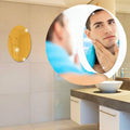 Oval self-adhesive bathroom mirror sticker on a tiled wall.
