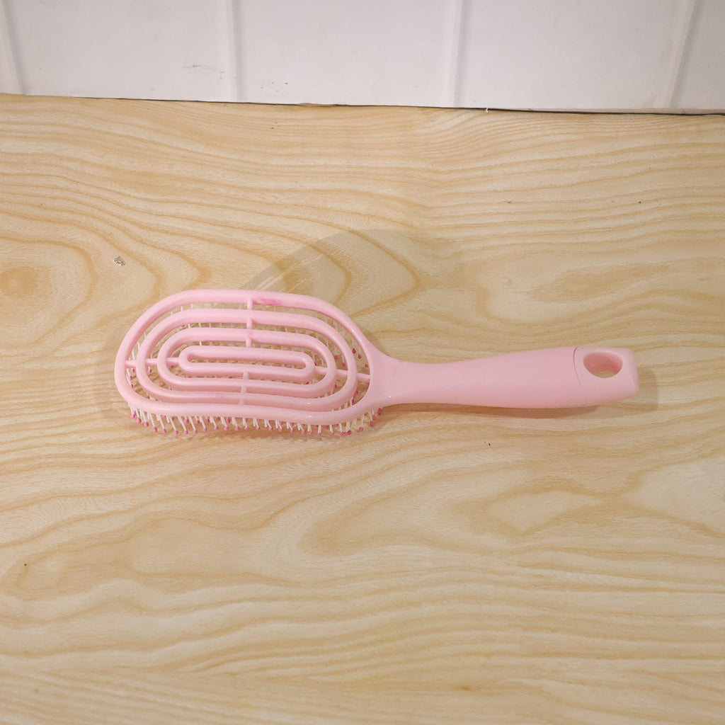 Woman brushing her hair with pink curved styling brush