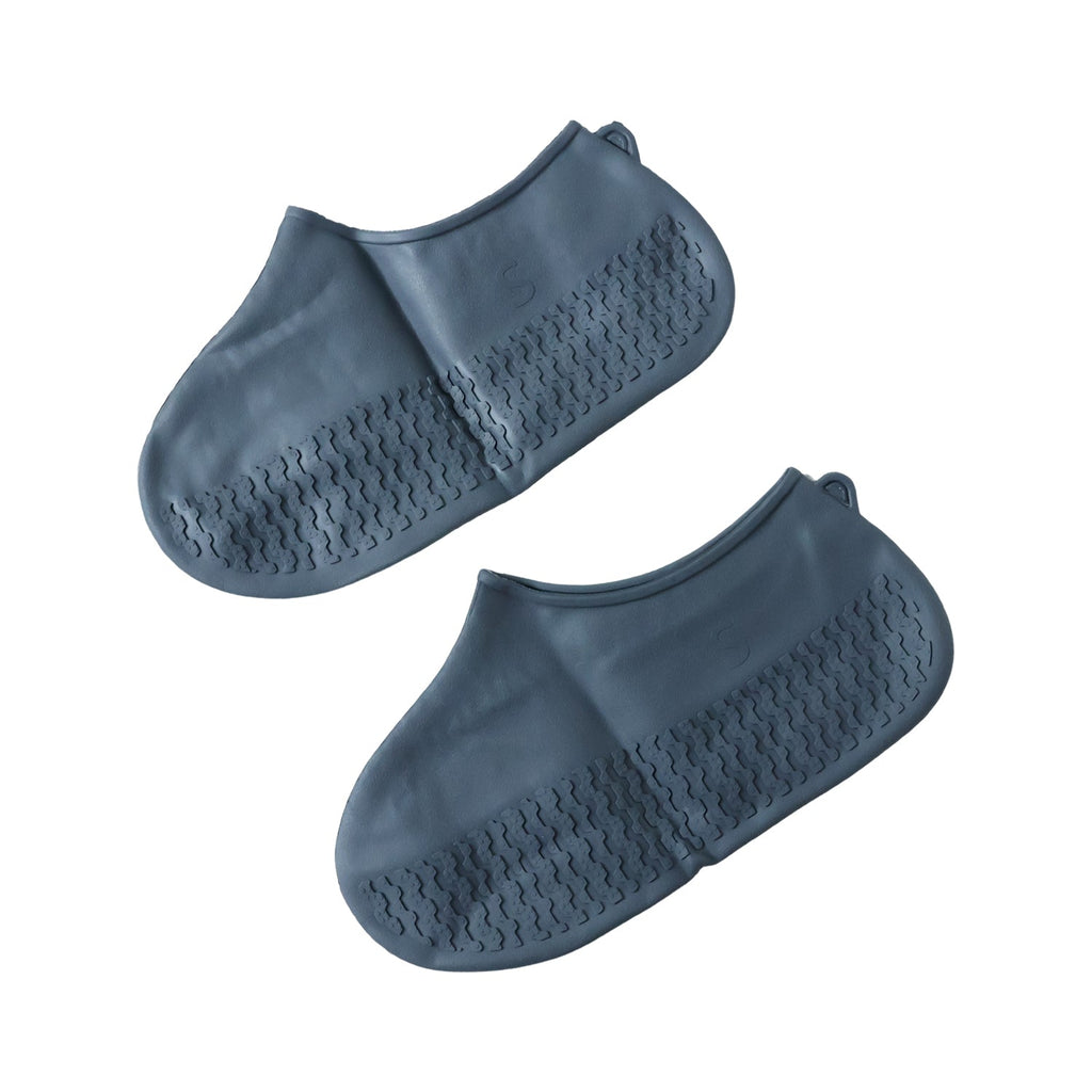 Silicone shoe cover with visible anti-skid sole pattern on a wet, tiled surface.