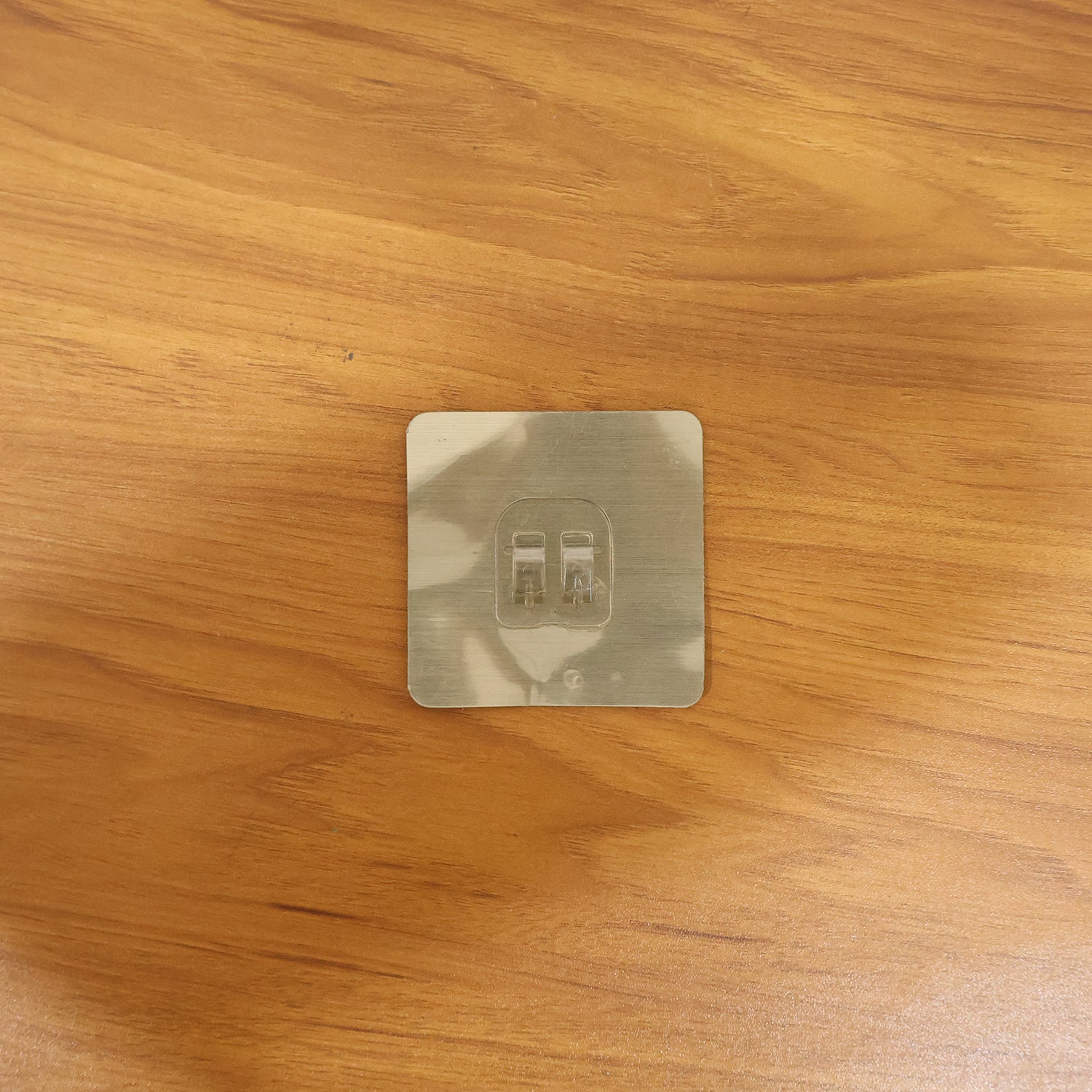 Transparent adhesive wall hook in a real-life home setting, holding various items.