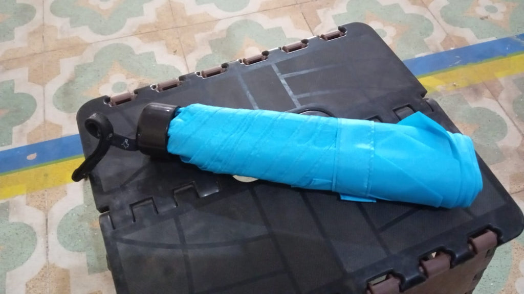 A hand holding the DrizzlePro 3-fold umbrella, illustrating its ergonomic design and convenient size.