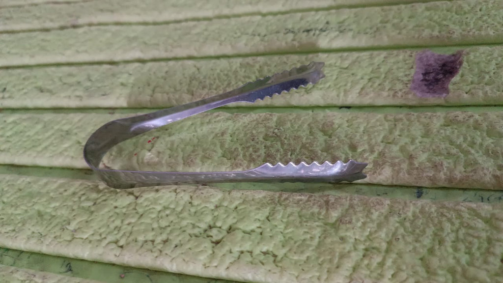 Stainless steel tongs resting on a rustic wooden surface, highlighting versatility.