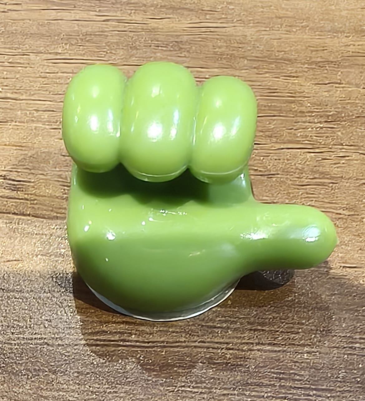 Angled view of the green hand-shaped flexible wall clip holder
