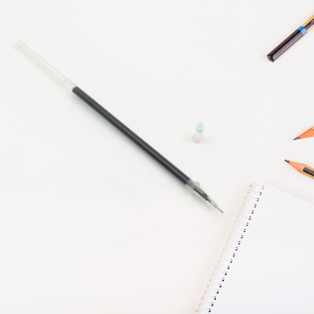 A single black pen refill lying on a surface, emphasizing its compact size.