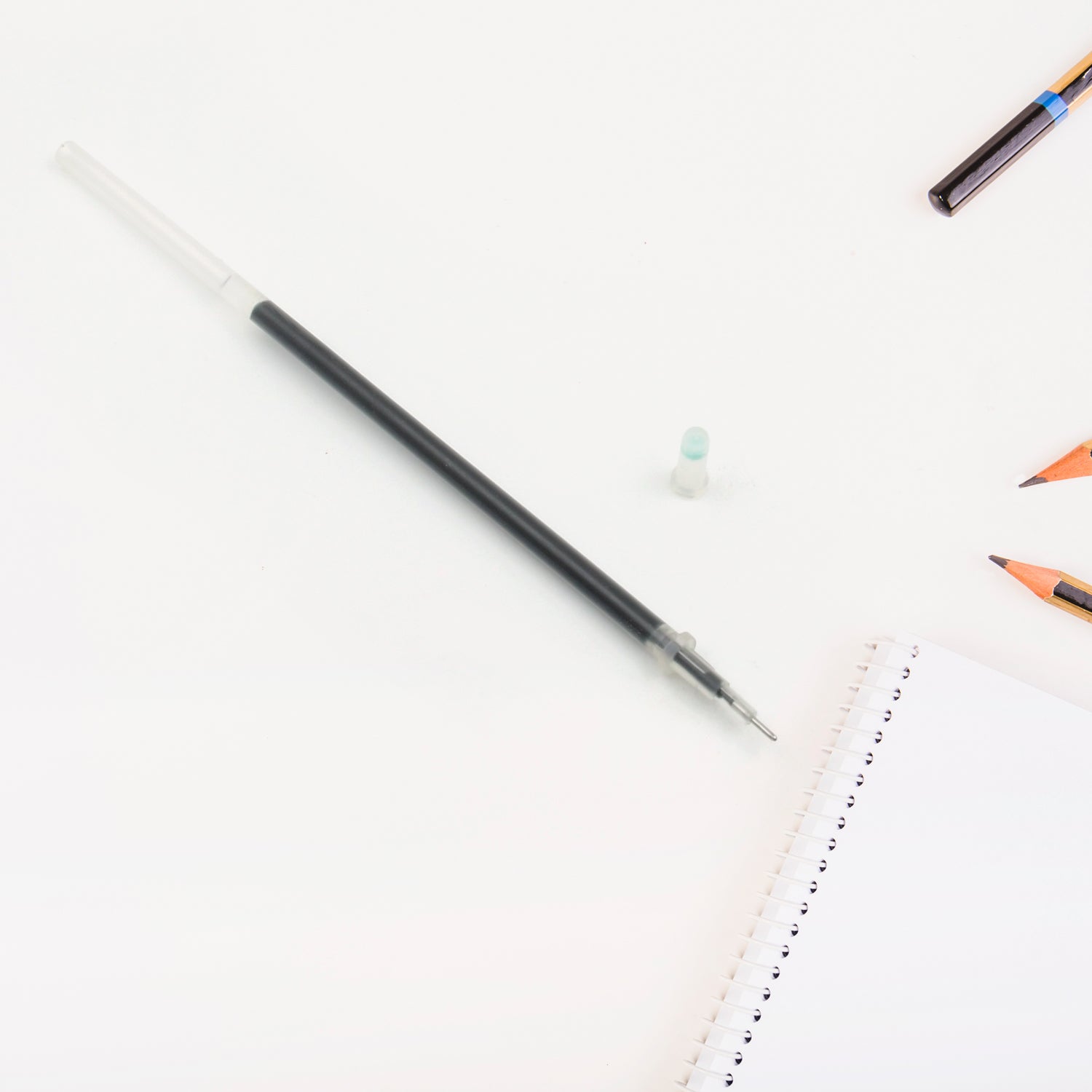 A single black pen refill lying on a surface, emphasizing its compact size.