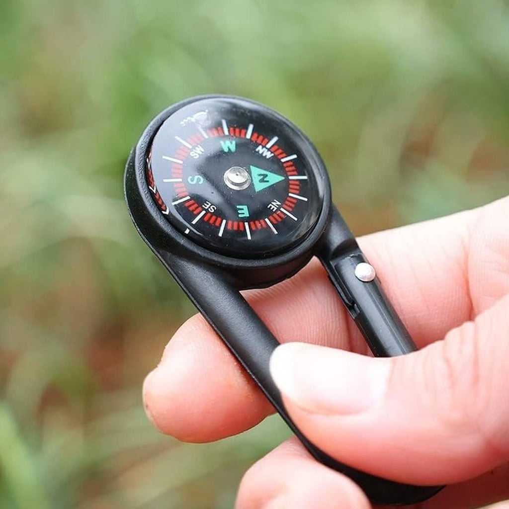 Mini compass with clip attached to a backpack strap, showing its compact size for outdoor use.